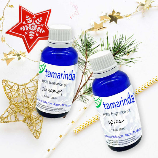 Two bottles of Tamarinda fragrance oil with Christmas decorations on a white background